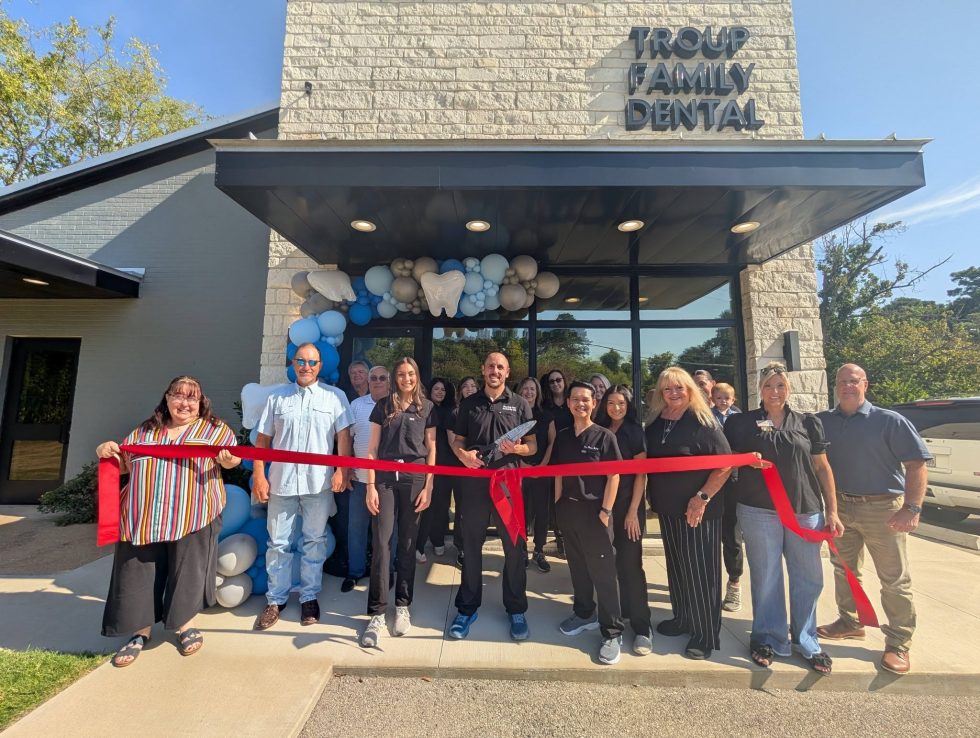 Troup Family Dental staff, community members and representatives of the Troup Chamber of Commerce gather for a ribbon-cutting during the dental practice's grand reopening celebration.